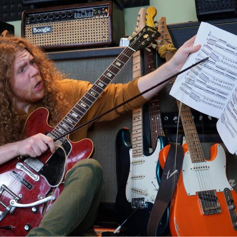 Sean Ashe working through written music with a guitar