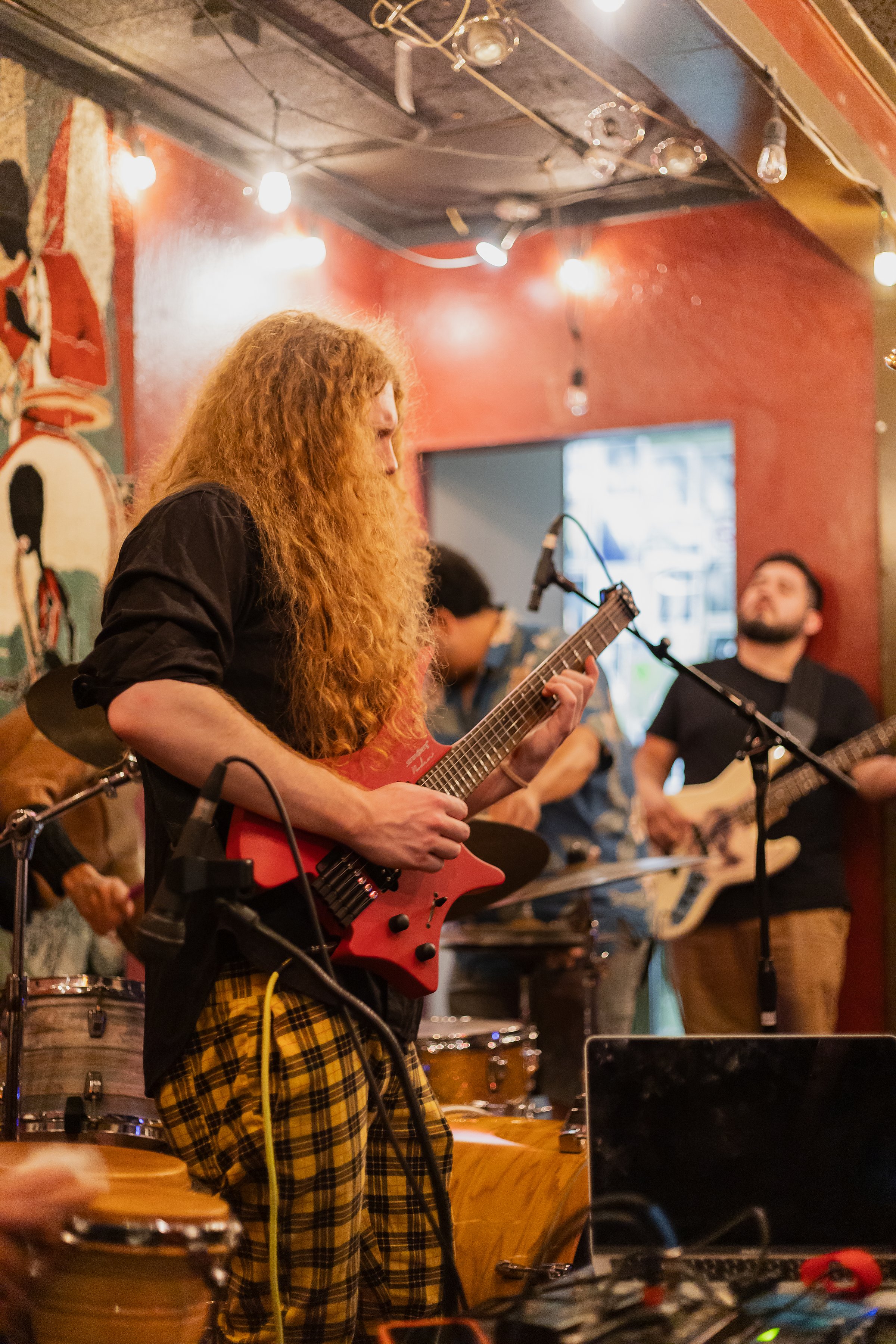 Sean Ashe performing electric guitar with a live band at the Torch Club.