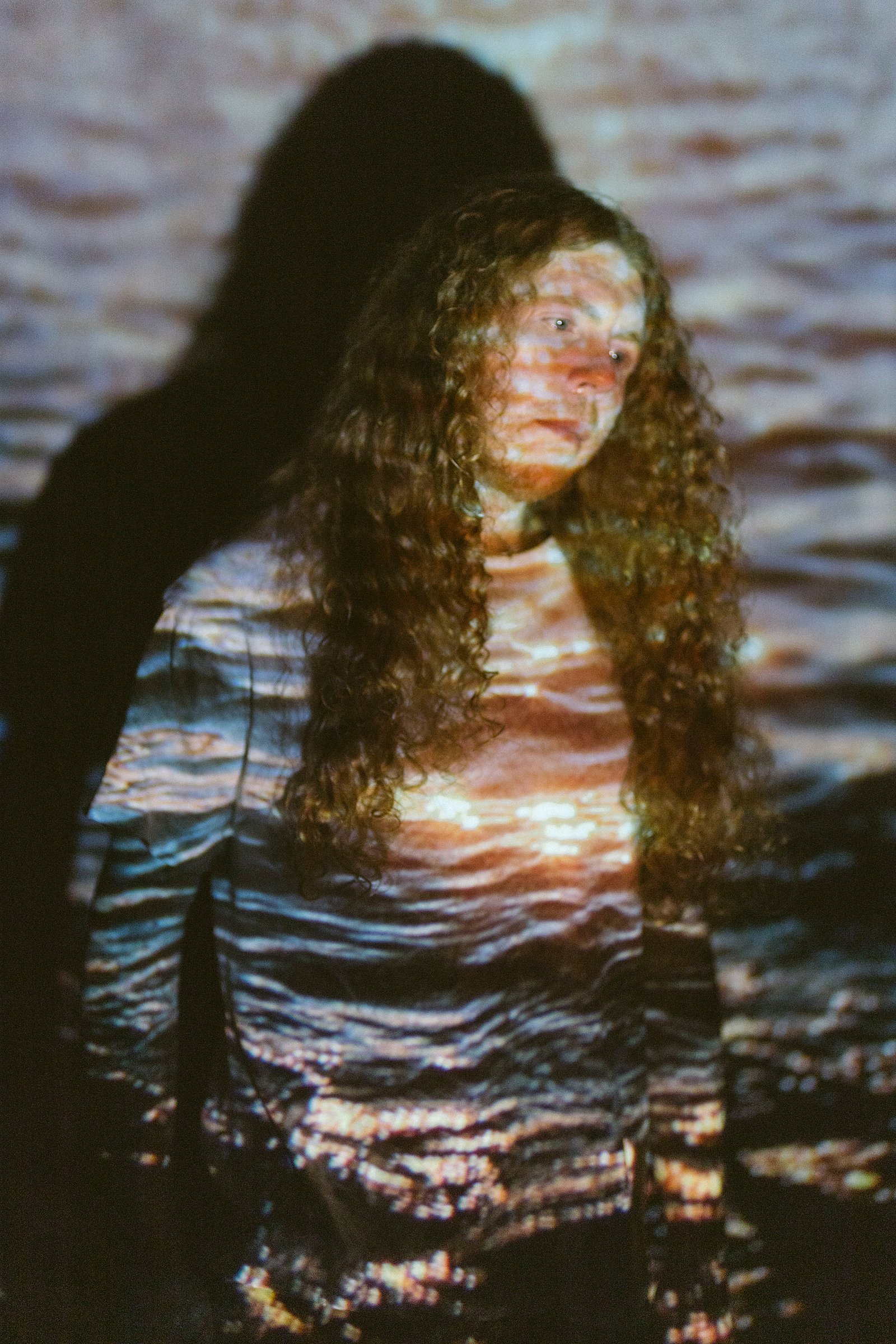 Sean Ashe lit by a projected water texture in an experimental portrait.