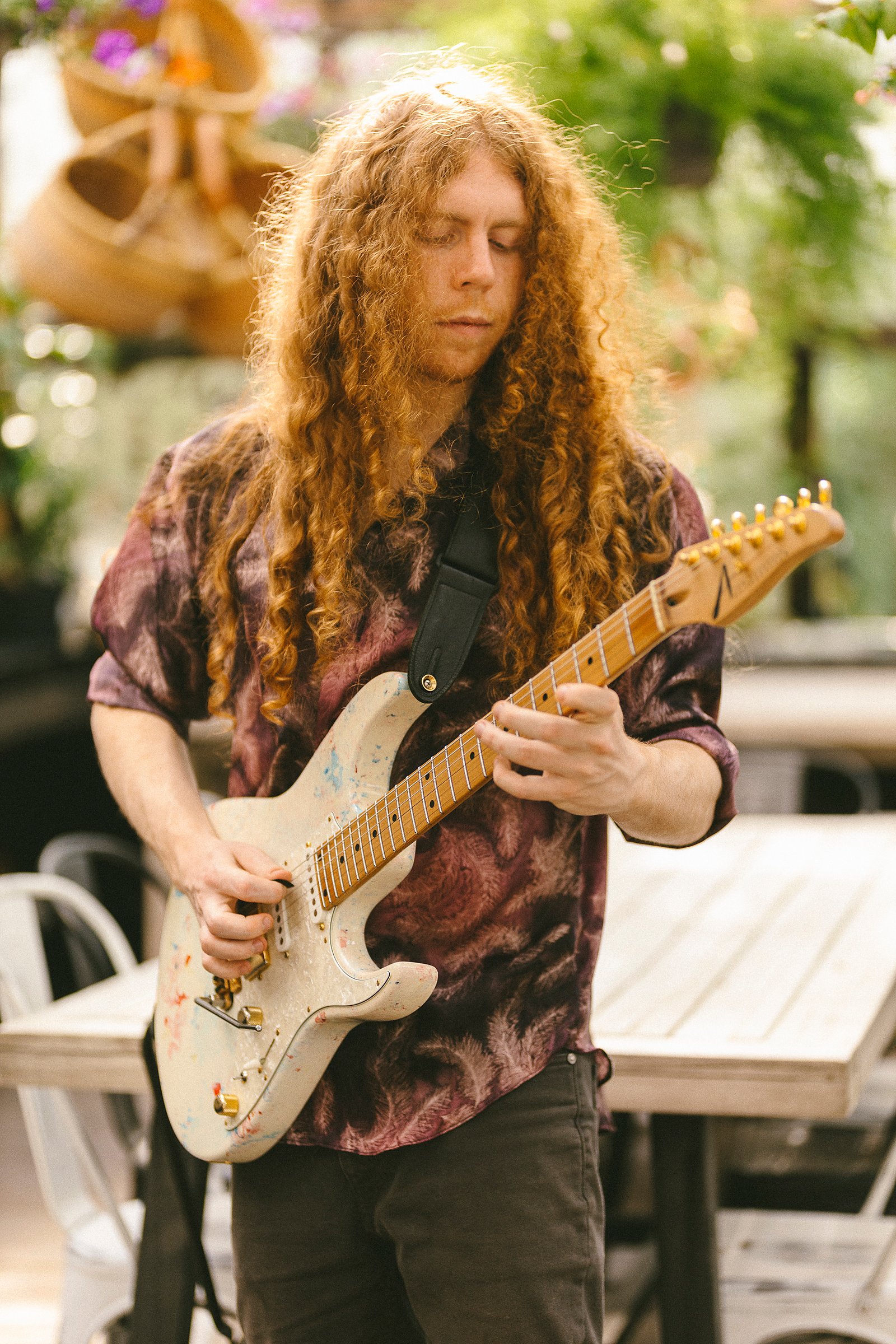 Sean Ashe playing a white electric guitar outdoors in soft natural light.