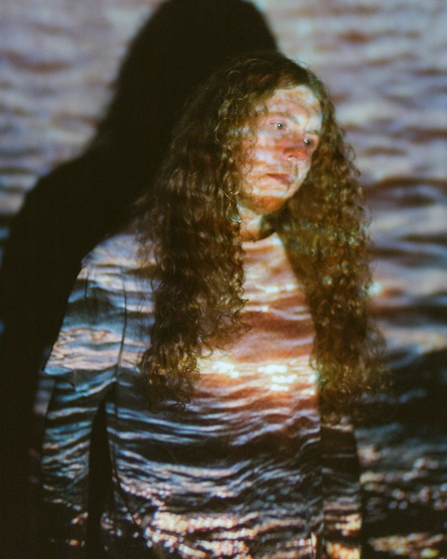 Sean Ashe lit by a projected water texture in an experimental portrait.