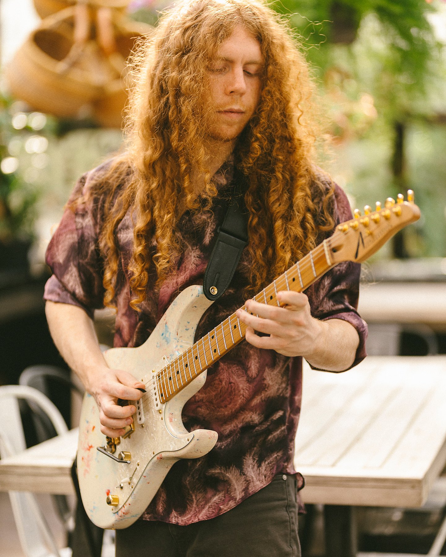 Sean Ashe playing a white electric guitar outdoors in soft natural light.