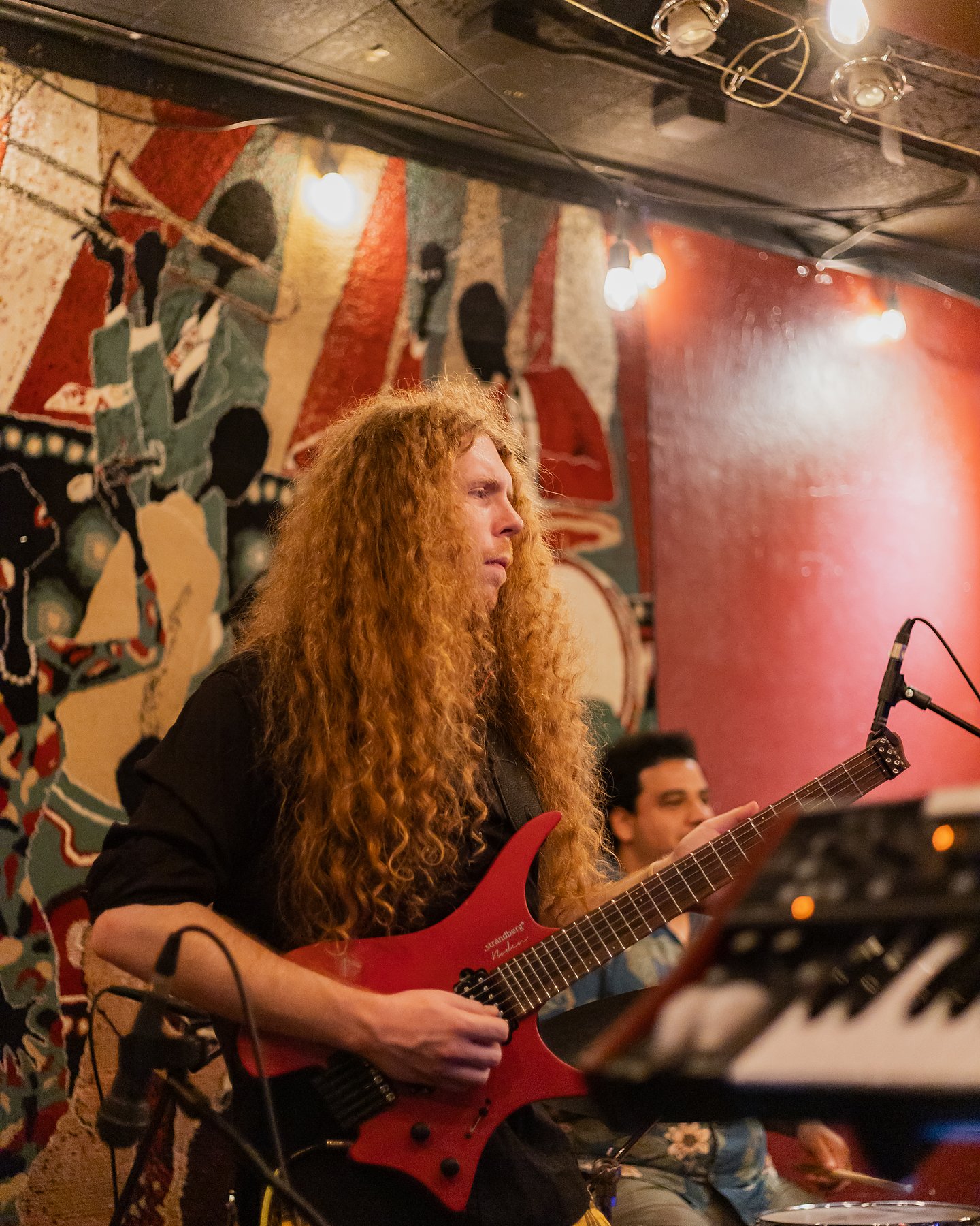 Sean Ashe playing a red electric guitar during a live performance at the Torch Club.